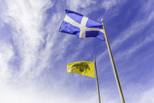 Greek And Byzantine Flags Waving On The Air Against Cloudy Sky