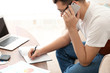 © Africa Studio - Young man talking on phone while working at home