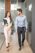 © Bojan - Beautiful young business woman and man walking through office hall and talking.