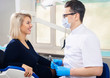 © ANR Production - Portrait of young smiling dentists and female patient in dental stomatology clinic with white background