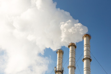 Smoking pipes making clouds against blue sky background. Dioxide air contamination. Environmental pollution