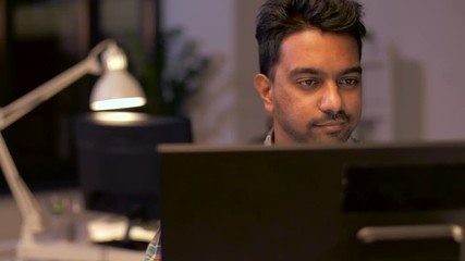 creative man with laptop working at night office