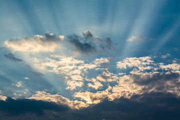 Wall Mural - sun rays against a blue sky in the clouds
