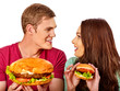 Couple eating fast food. Man and woman eat hamburger with ham. Friends holding burders junk on isolated. Loving couple prefers fast food to homemade dinner. Health problems due to malnutrition.