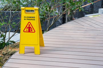 Wall Mural - wet floor sign, yellow plastic sign with cleaning in progress text on foot path