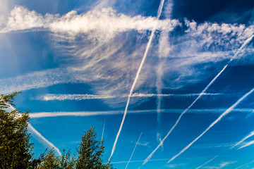 The photo of a group of crisp and blurred white traces of airplanes in a blue sky was made in Brussels in Belgium 