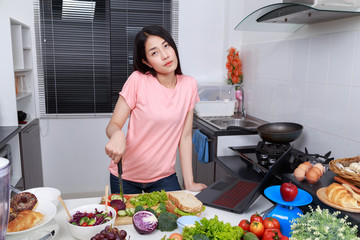 Sticker - woman cooking and looking with laptop in kitchen room