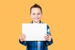 Cute young smiling preschooler boy holding up blank sign with copy space isolated on ogange background.