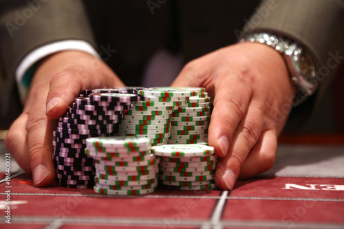 Fotografie, Obraz Player at gambling table pusing large stack of chips