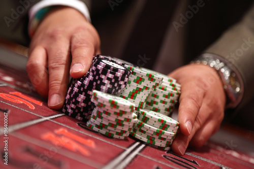 Fotografie, Obraz Player at gambling table pusing large stack of chips