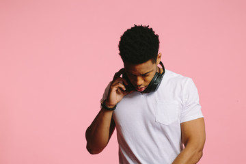 Wall Mural - Portrait of a cool African American guy in white shirt on pink background