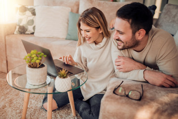 Young couple relaxing on sofa with laptop