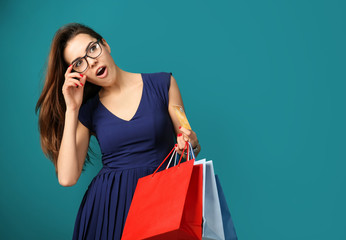 Wall Mural - Young woman with shopping bags and credit card on color background