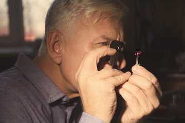 Wall Mural - Jeweler examining gem in workshop