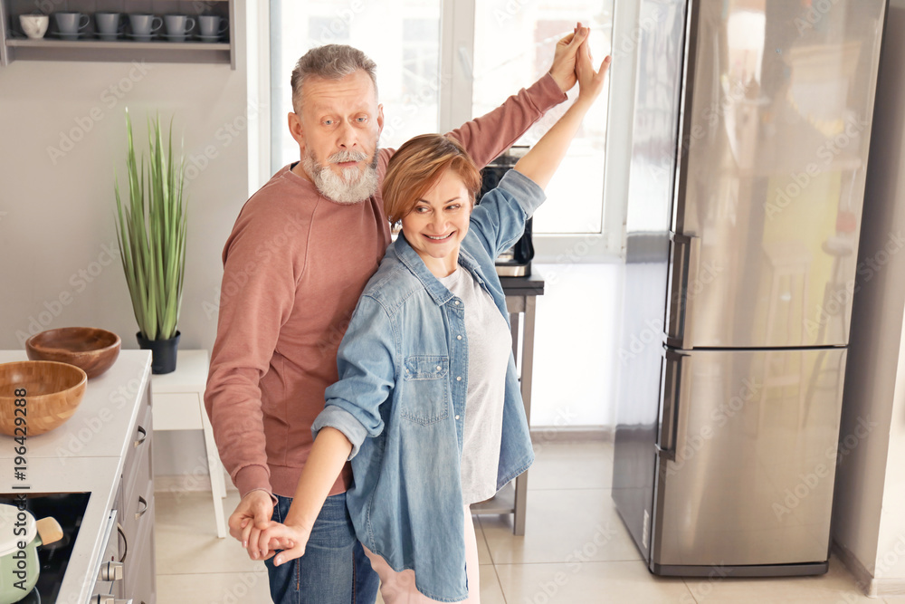 Happy mature couple dancing in kitchen