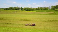 An Aerial Of Amish Farmers Tending Their Fields With Horse And Plow.
