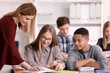 © Africa Studio - Group of teenagers doing homework with teacher in classroom