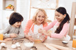 © freeograph - Young grandmother and grandchildren break eggs into bowl in kitchen. Llittle girl is learning to cook.