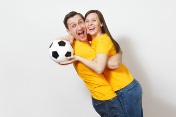 Wall Mural - Fun crazy cheerful emotional young couple, woman, man, football fans in yellow uniform cheer up support team with soccer ball isolated on white background. Sport, family leisure, lifestyle concept.