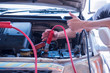 A jump start, act of using a charged battery with a new one or another car with a big pair of battery jumper cable, safely jump start a dead battery concept.