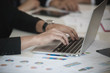 © xreflex - Hand of businessmen used laptop while Group discussing on stockmarket charts at office desk, they are business analyzing. brainstorming, teamwork, meeting concept..