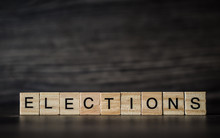 The Word Elections, Consisting Of Light Wooden Square Panels On A Dark Wooden Background