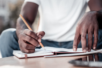 preparation process. scaled up look on hands of a young man holding a pencil and writing down some n