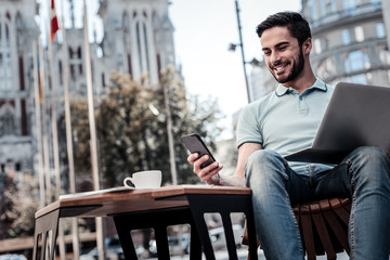 good news is the best news. low angle shot of a bearded guy grinning broadly while sitting outdoors 