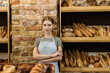 © LIGHTFIELD STUDIOS - beautiful young baker with crossed arms standing at pastry store