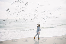 Stylish Girl Running On Winter Seashore With Seagulls
