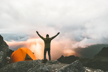 Wall Mural - Man traveler happy raised hands on mountain top near of tent camping outdoor Travel adventure lifestyle success concept hiking active vacations enjoying sunset view