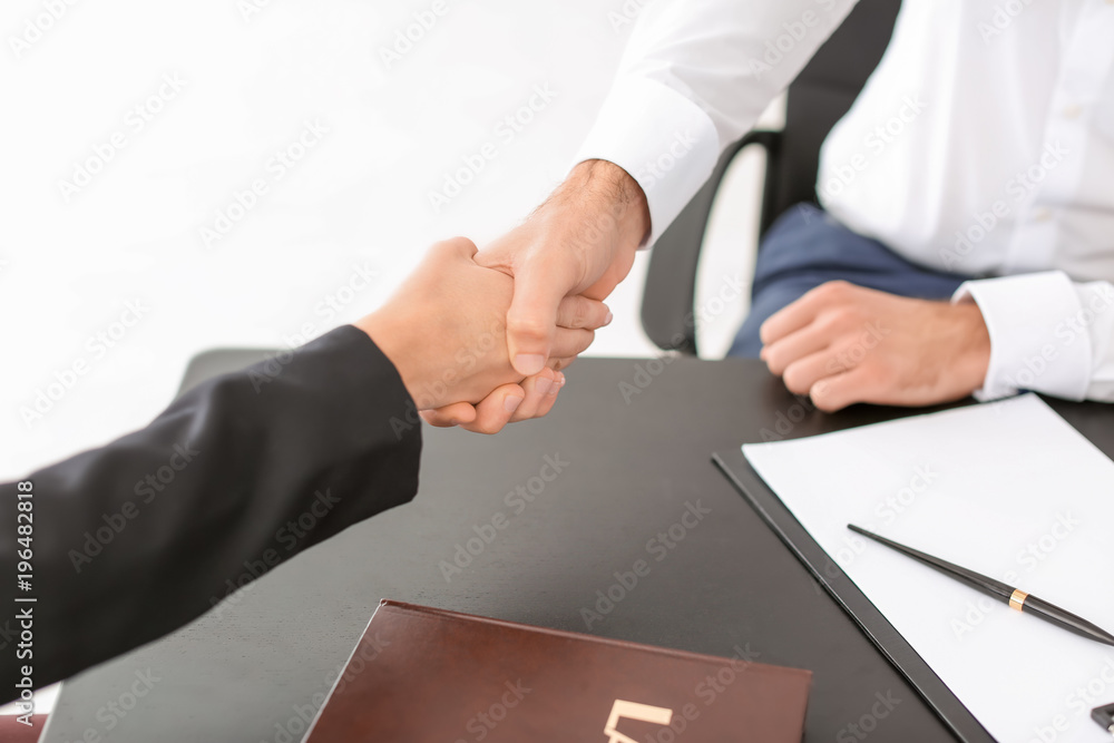 Lawyer shaking hands with client in office, closeup