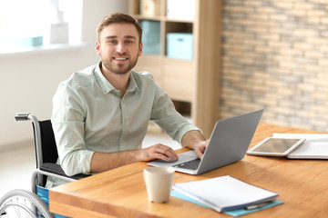 Wall Mural - Young man in wheelchair at workplace