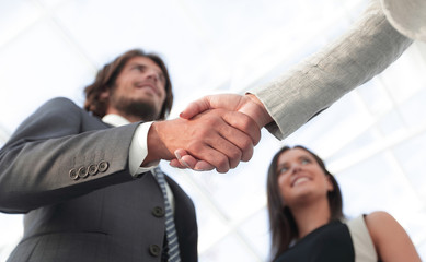 Businesspeople  shaking hands against room with large window loo