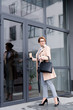© LIGHTFIELD STUDIOS - stylish businesswoman in coat with coffee to go entering business center