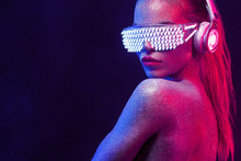 Beautyful Girl With Glitter And Sparkles On Her Face And Body. Portrait Of Sexy TDJ With Headphones And Neon Sunglasses
