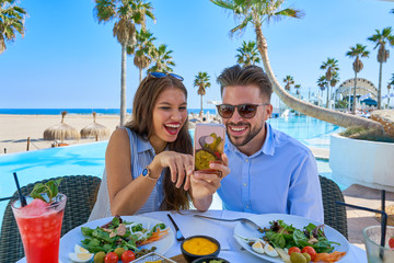 Wall Mural - Young couple with smartphone in pool restaurant