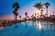 Resort pool in a beach with palm trees sunrise