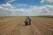 © sima - Farmer and packed bale of hay in field, early summer