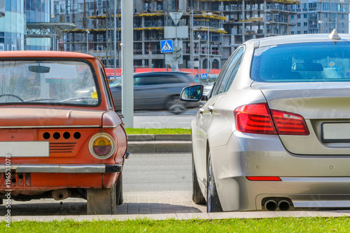 Rear view of two cars of different eras standing side by side in the city. The concept of technology development © v_sot