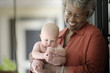 © Erickson Stock - Baby being held by a mature adult woman.