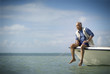© Erickson Stock - Mature man sitting on the edge of a boat fishing.
