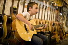 Boy Playing Guitar In Music Store