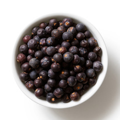 Poster - Dried juniper berries in white ceramic bowl isolated on white from above.