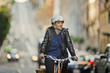 © Erickson Stock - Cheerful young woman explores the busy city streets on her bicycle.
