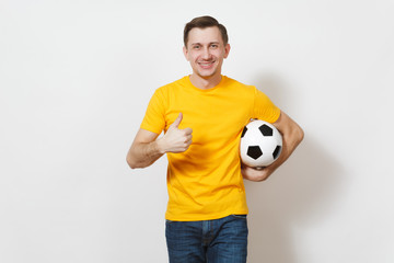 Wall Mural - Inspired young European man, fan or player in yellow uniform hold soccer ball, show thumb up, cheer favorite football team isolated on white background. Sport play football, healthy lifestyle concept.