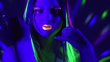 Wall Mural - Fashion model girl with colorful fluorescent makeup in ultraviolet neon lights. Female disco dancer in UV light. Night club, party. 4K UHD video footage. 3840X2160