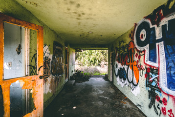 hallway of abandoned and condemned building with graffiti and broken door