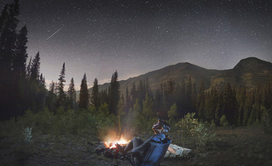 Woman at Campfire in Mountains Looking up at the Stars