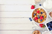 Cereal And Ingredients For A Healthy Breakfast Forming A Side Border Over A White Wood Background. Top View. Copy Space.
